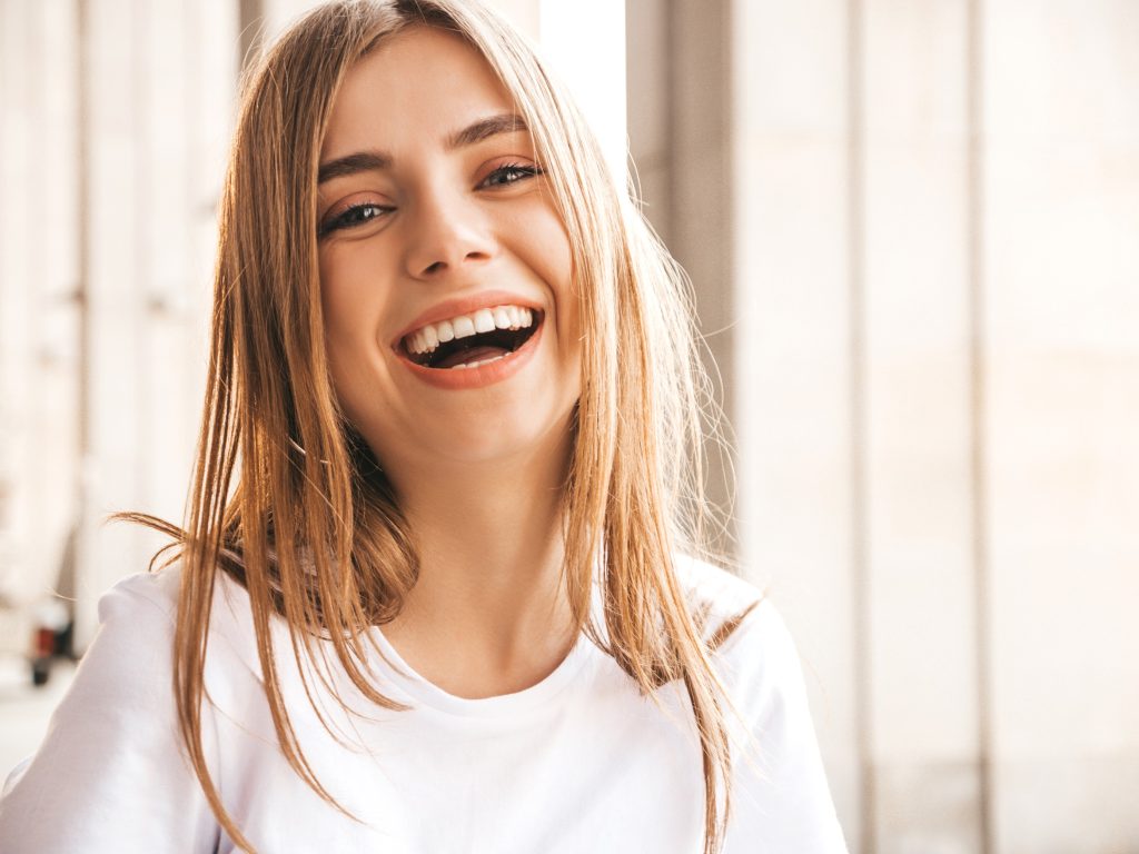 Portrait of beautiful smiling blond model dressed in summer hipster  clothes. Trendy girl posing in the street background. Funny and positive woman having fun